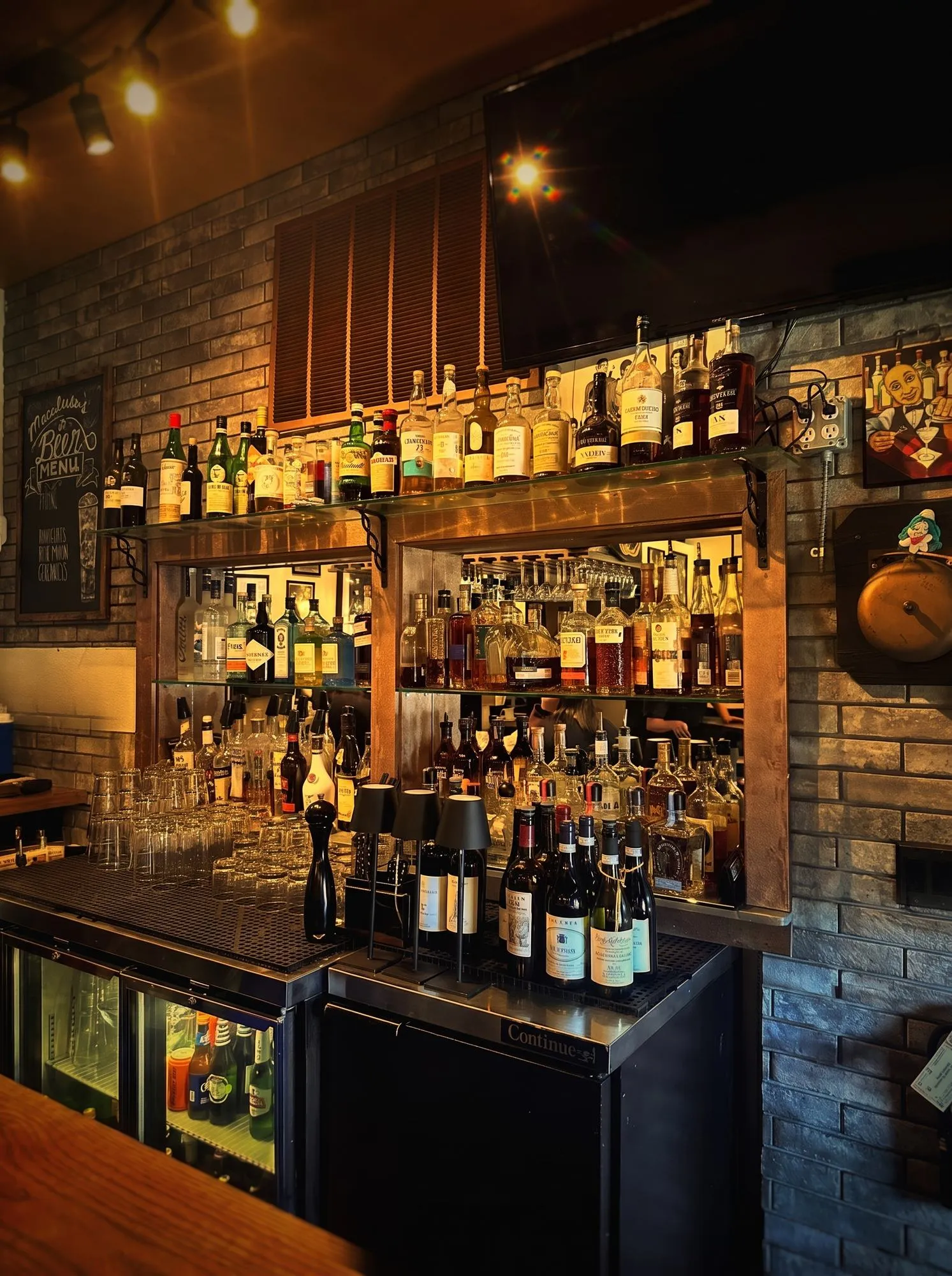 The backlit bar in the evening, bottles glowing along the back wall.